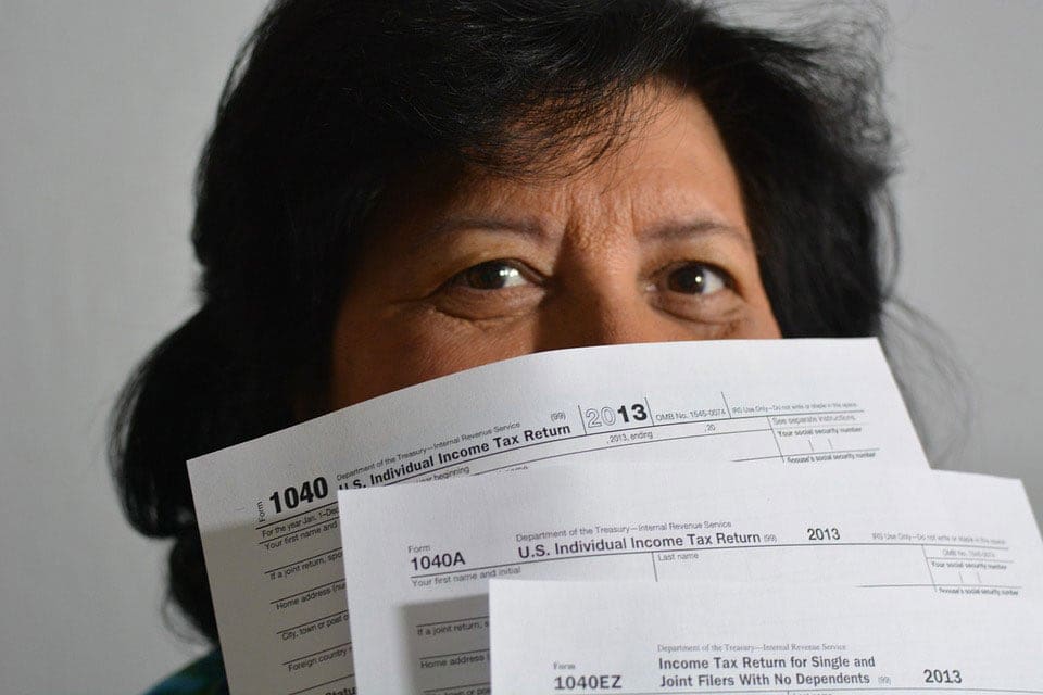 Older woman holding tax forms in front of her face