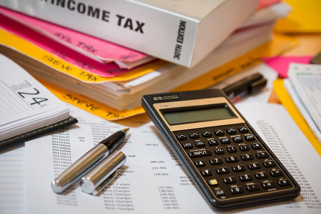 Income tax book and stack of file folders with calculator and pen