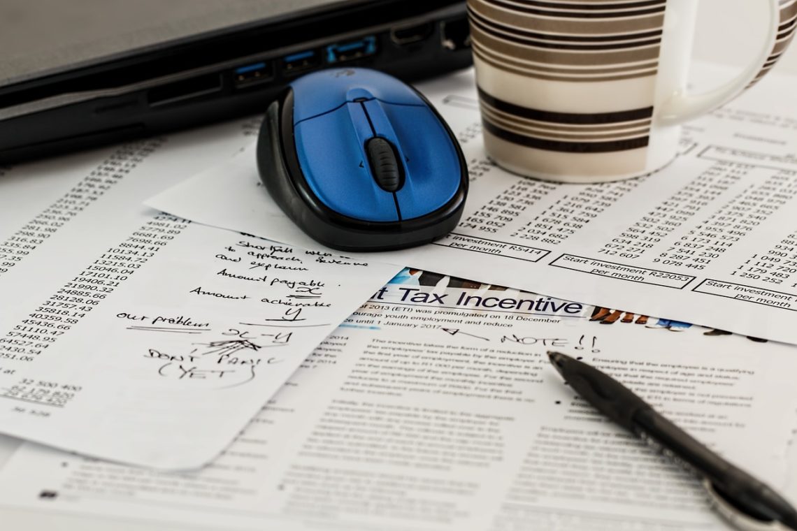 Pile of tax papers and pen with notes for taxes solutions